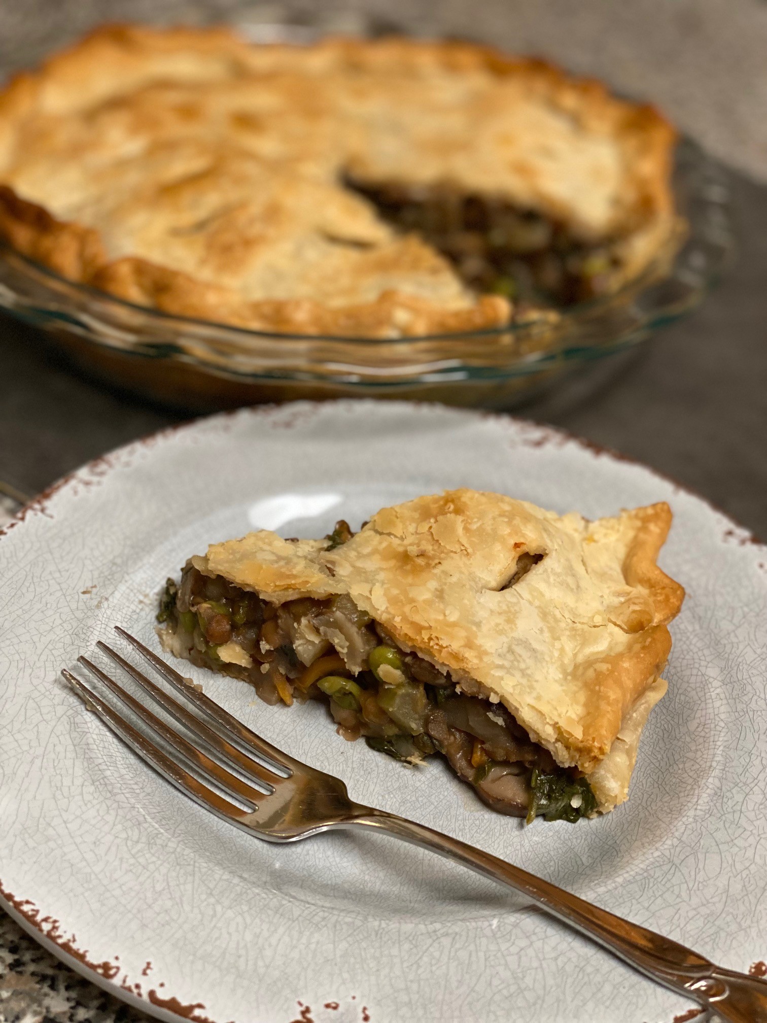 Slice of lentil pot pie in front of whole pie