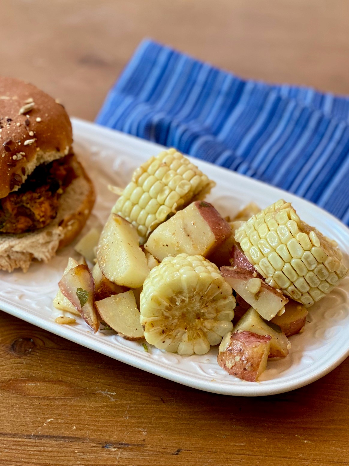 A dish with a black bean burger and a side dish of roasted vegetables and corn.