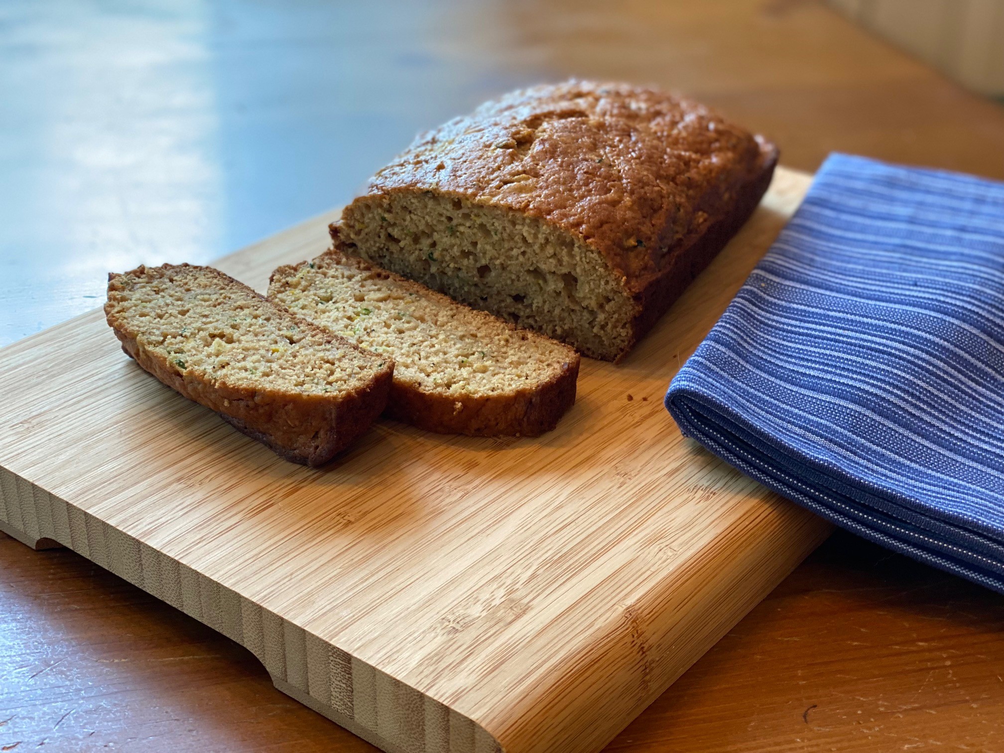 A loaf of zucchini bread sliced on a cutting board.