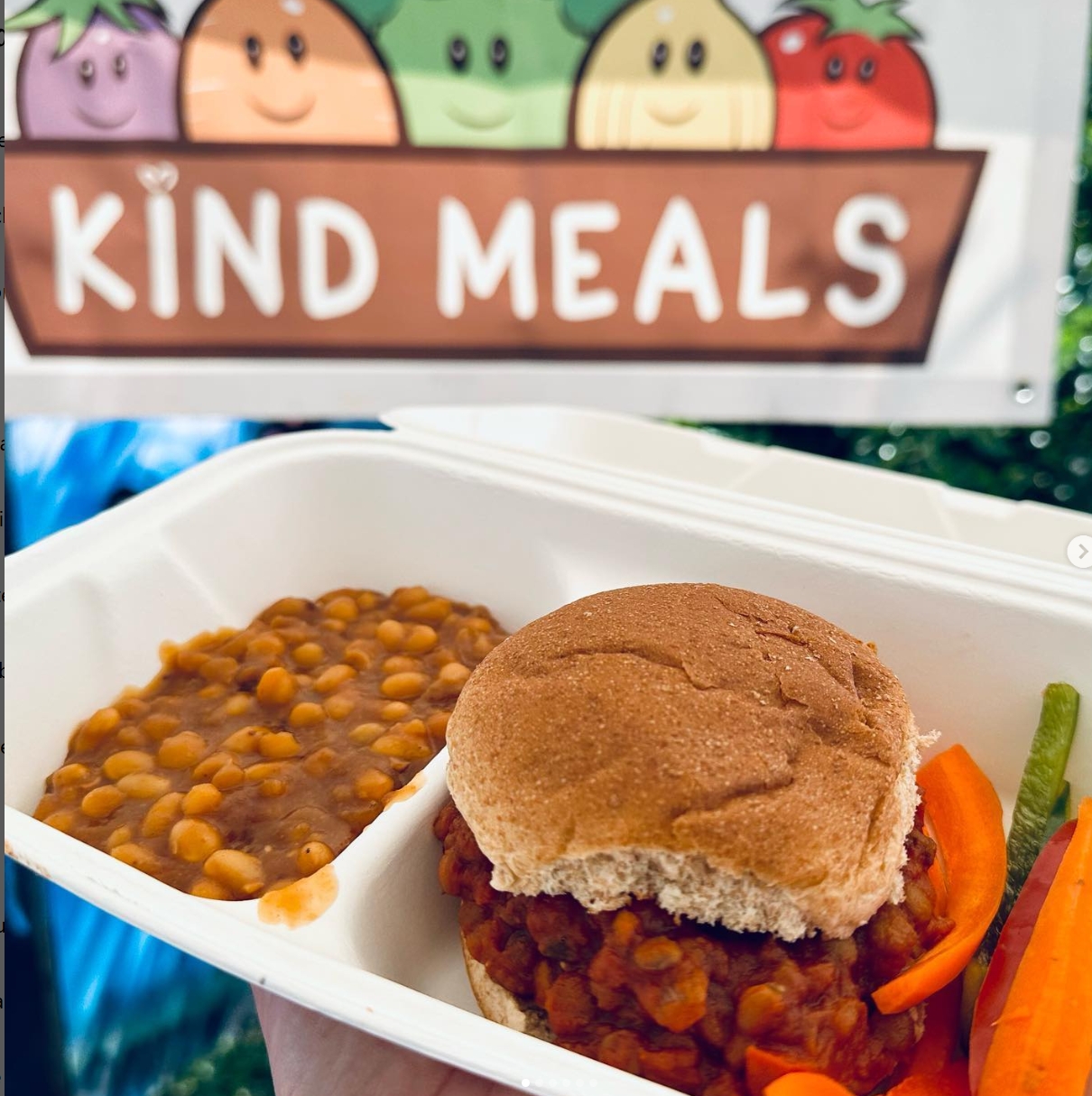 A tray of food in front of a sign with a logo for Kind Meals